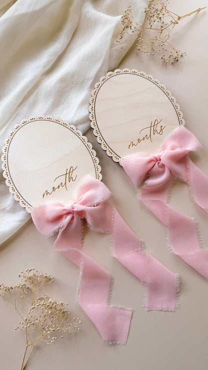 Two lace-trimmed signs engraved month and months